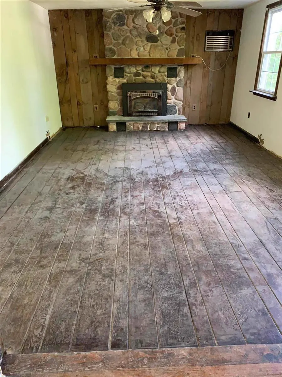 Wide plank floor, gray and worn, in a room with a stone fireplace